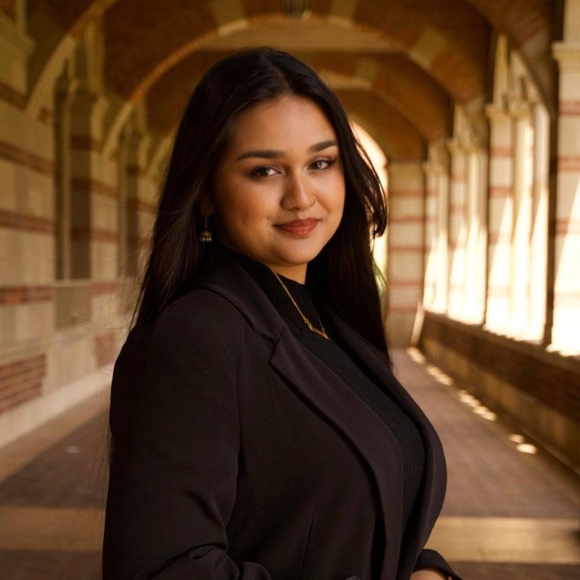 Professional headshot of Mehreen Suzaan smiling in a black blazer.
