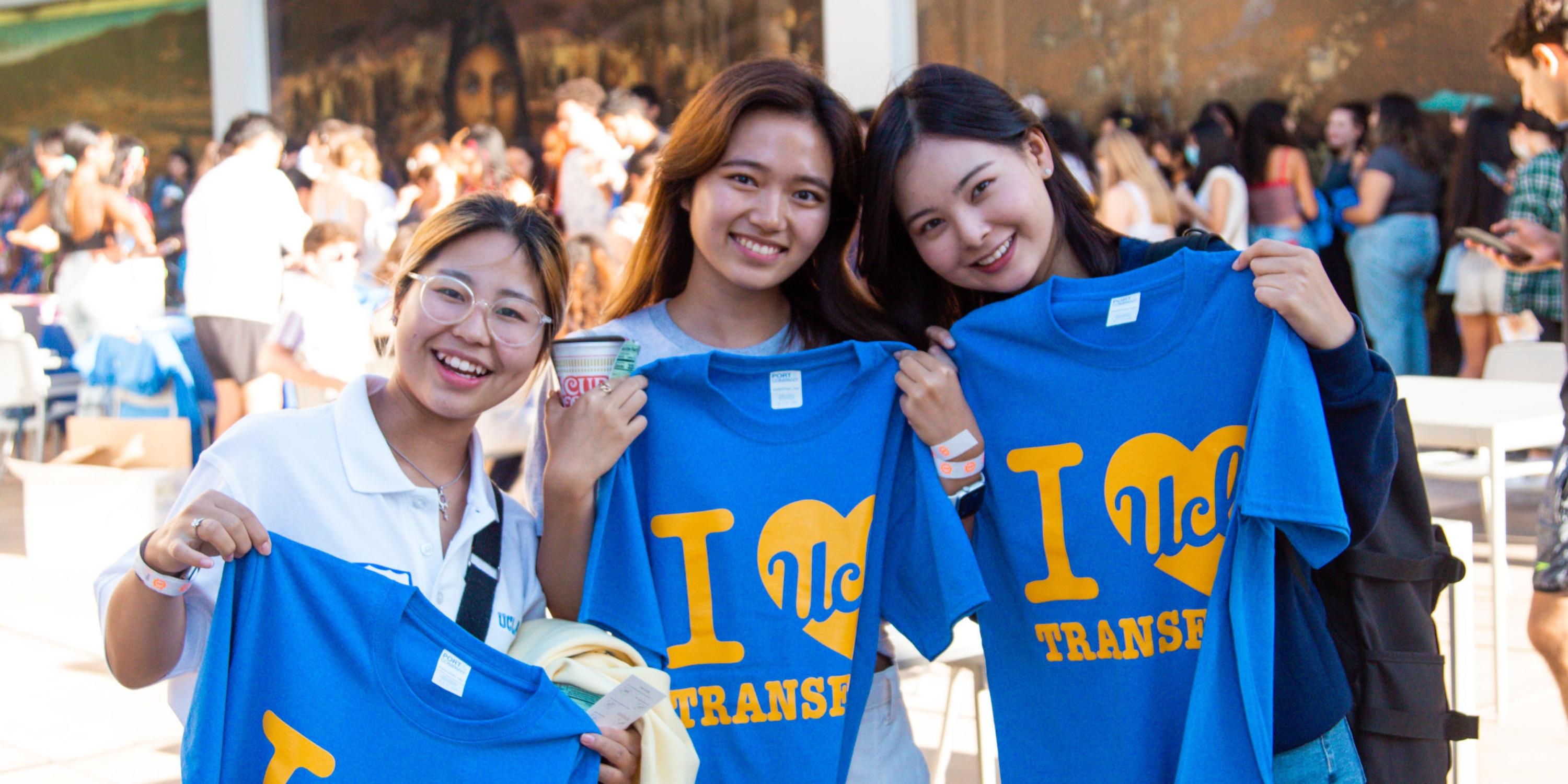 Three girls holding "I love UCLA Transfers" tshirt