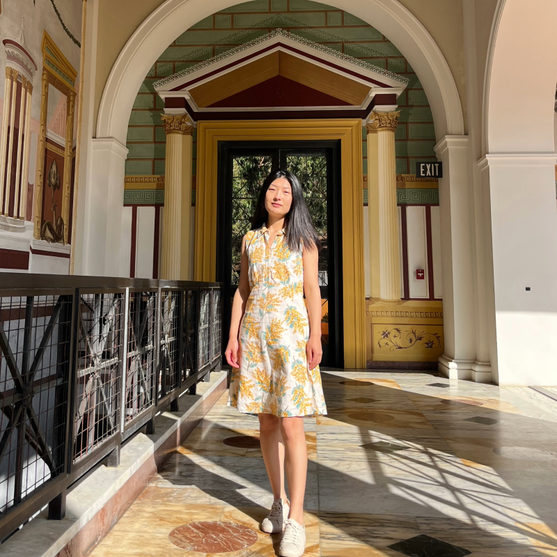 Picture of Yiping Wang smiling in a yellow floral dress.