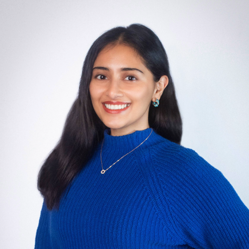 Picture of Sanjali Mitra smiling in a blue sweater.